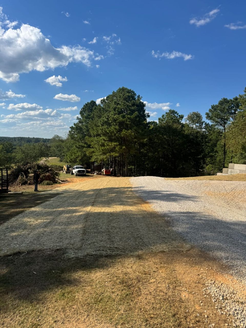 New gravel driveway and graded, seeded yard with concrete block retaining walls in the background
